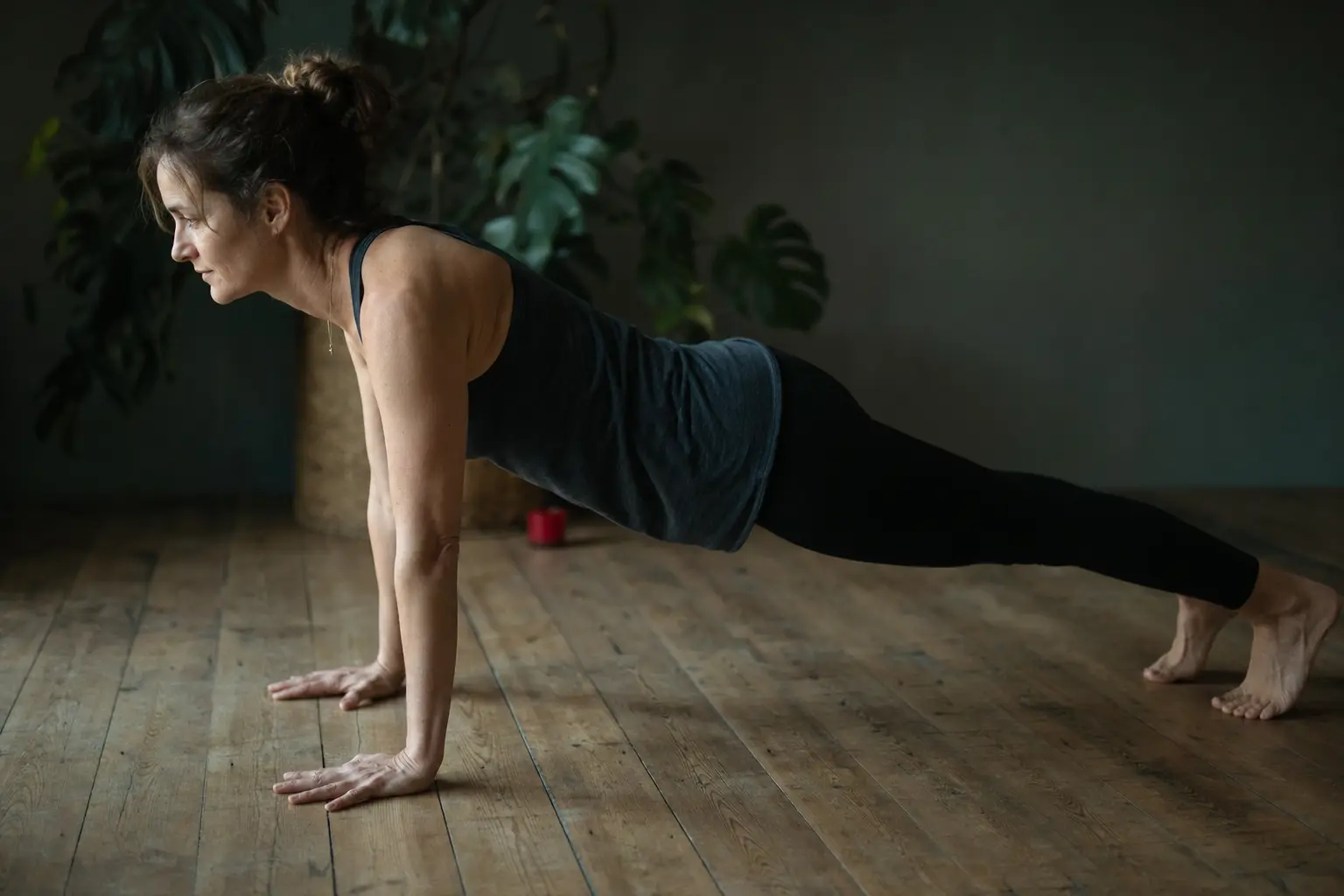 Một người ở tư thế plank hít đất trên sàn gỗ.